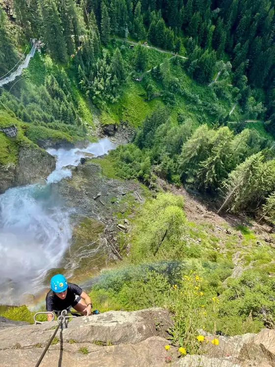 Klettern über einem Wasserfall in einer grünen Berglandschaft